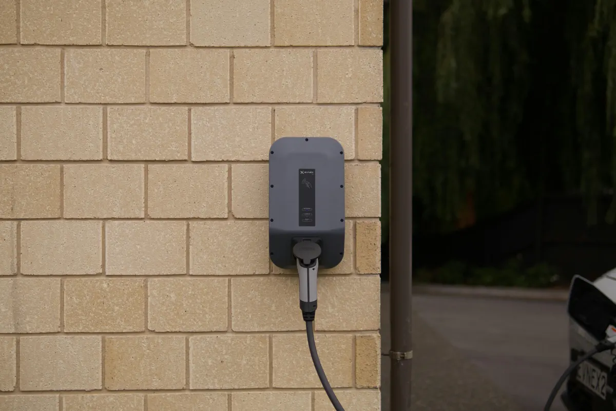 Level 2 EV charger mounted on an exterior wall and connected to a vehicle